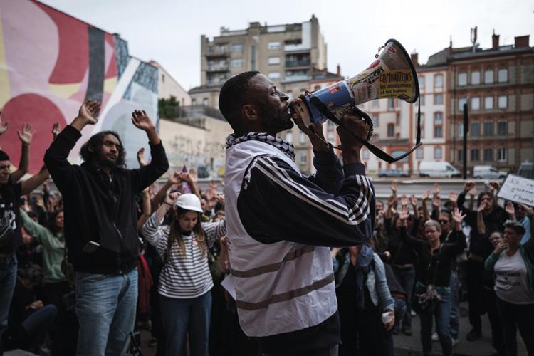 Foule en manif. Homme parle dans un mégaphone au premier plan