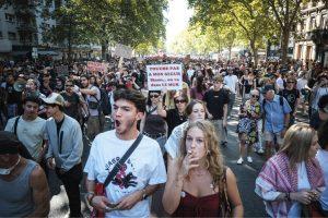 Foule en manif, au premier plan une personne fume et une personne crie