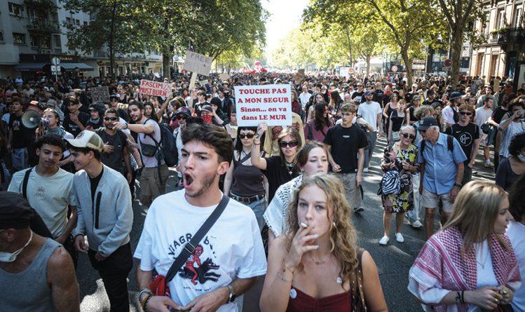 Foule en manif, au premier plan une personne fume et une personne crie