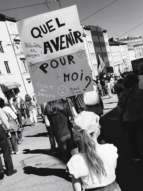 Jeune photographiée de dos en manif. Elle tient une pancarte "Quel avenir pour moi ?"