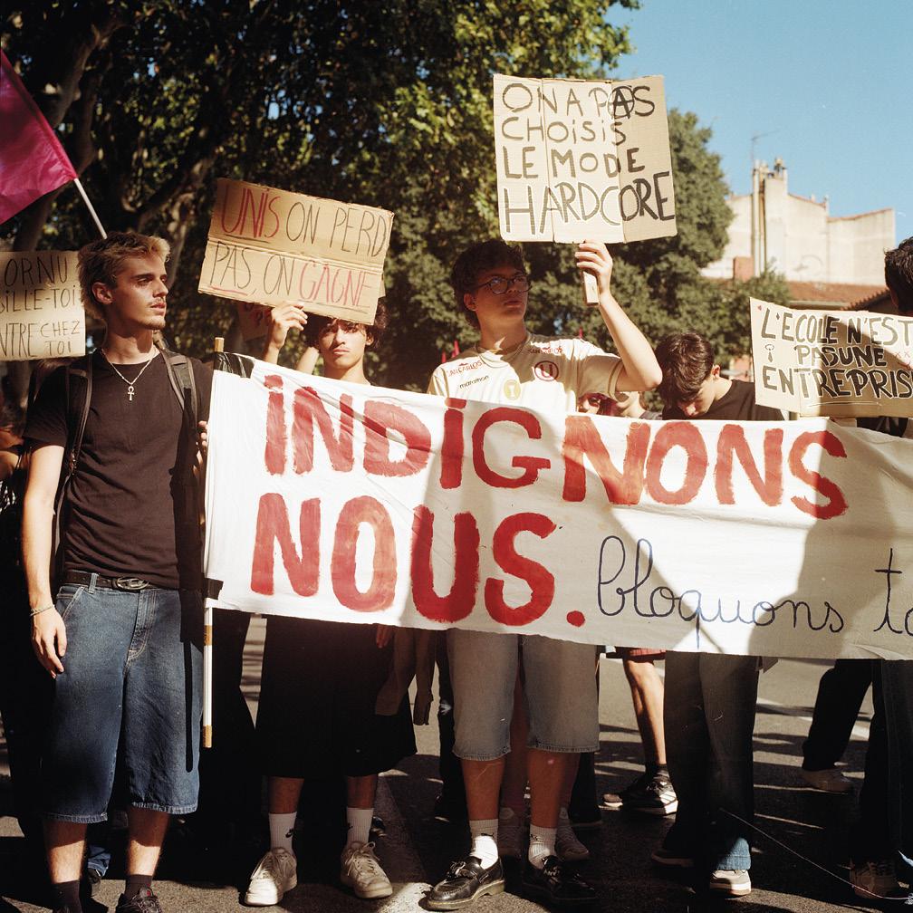 Des jeunes qui tiennent une banderole "Indignons-nous" et des pancartes "On a pas choisi le mode hardcore" et autres dans la rue