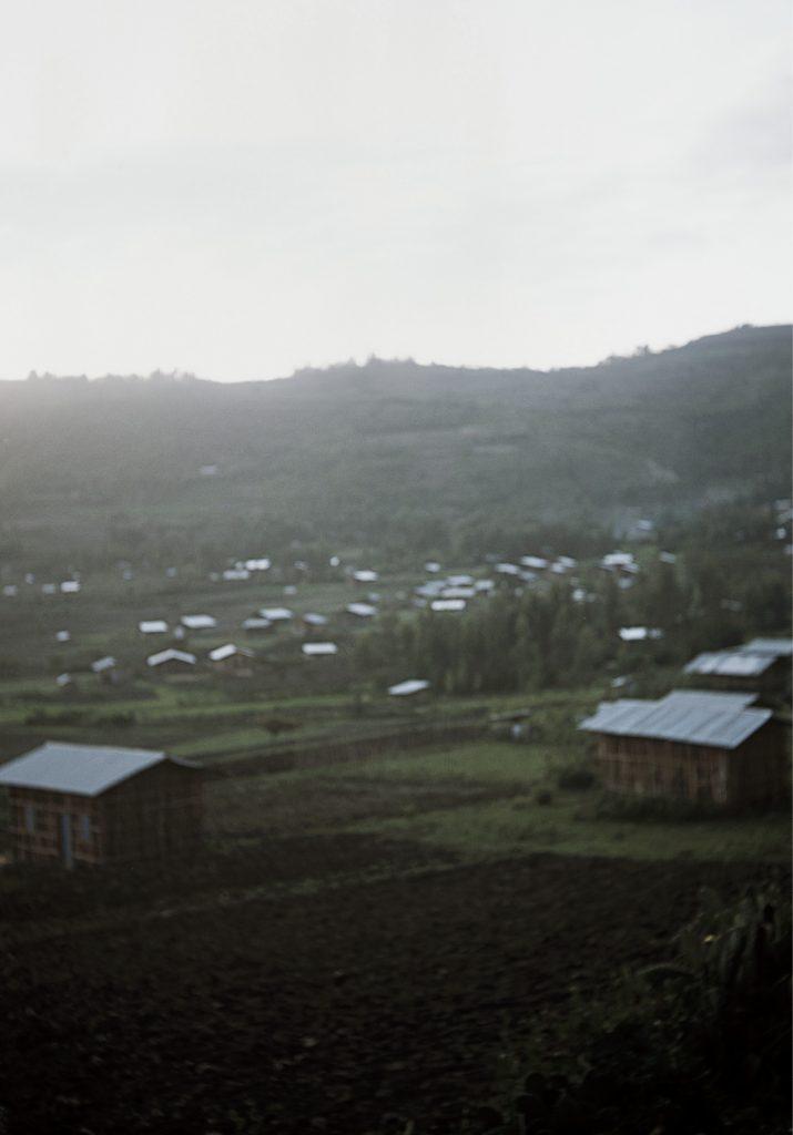 photo floue de paysage, on distingue des toits d'habitation et des collines