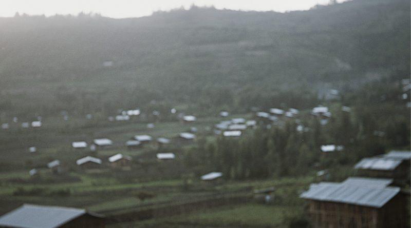 photo floue de paysage, on distingue des toits d'habitation et des collines