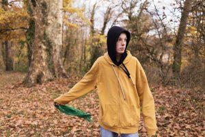photo d'un garçon tenant un foulard dans une forêt et regardant en l'air