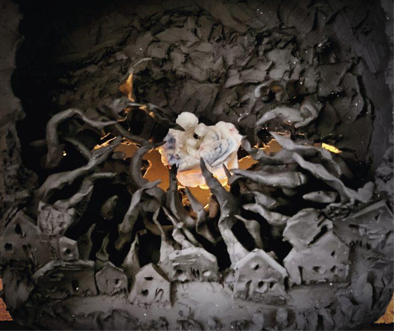 photo d'une sculpture&nbsp;: personnages en blanc au milieu d'un village noir. Flammes.
