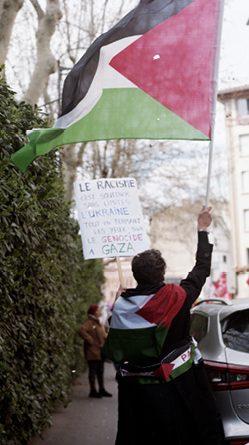 manif où quelqu'un tient un drapeau palestinien