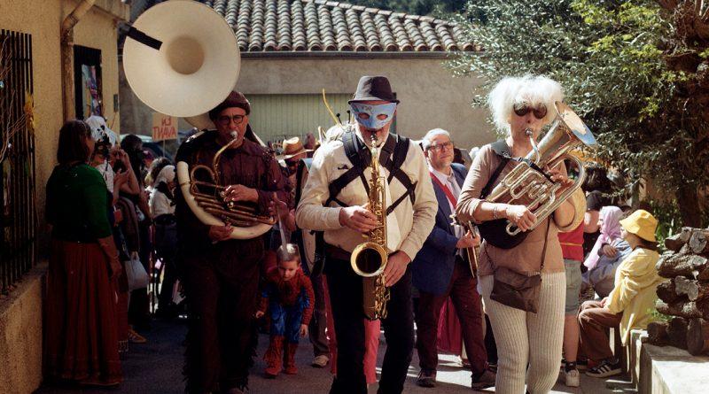 personnes déguisées jouant d'instruments à vent en marchant dans une rue de village