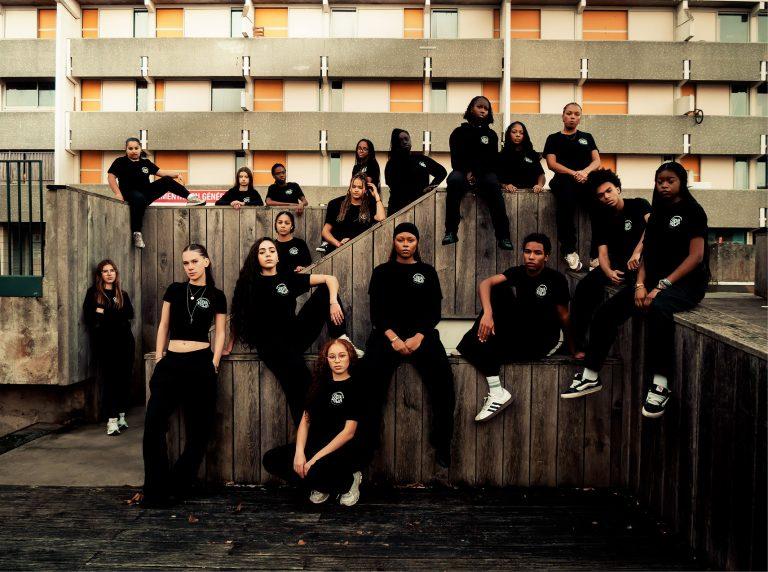 Jeunes danseuses habillées en tenue noire de Fidia Diala, sur des murets devant un immeuble