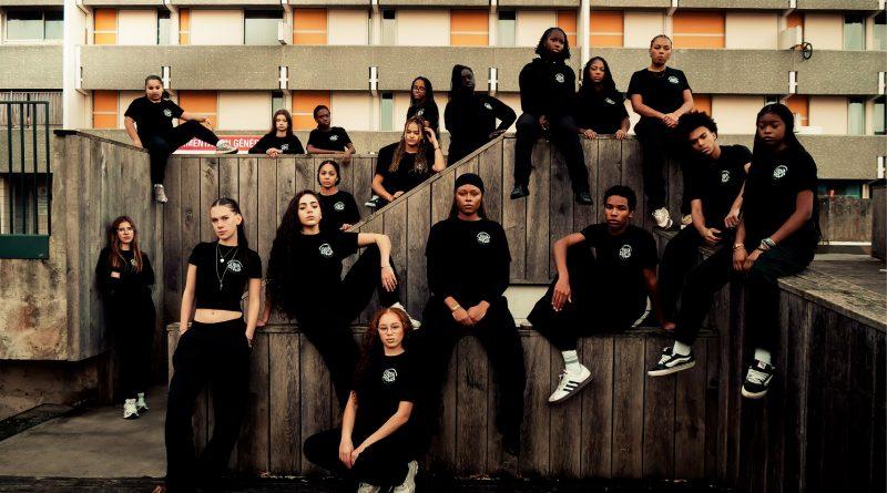 Jeunes danseuses habillées en tenue noire de Fidia Diala, sur des murets devant un immeuble