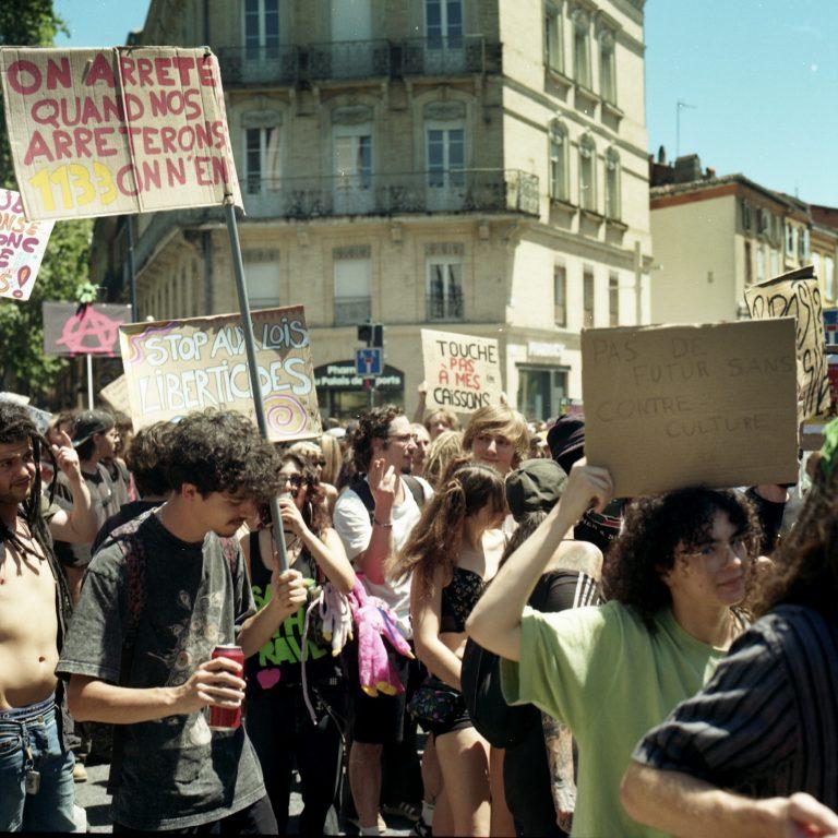 photo argentique de jeunes manifestants avec des pancartes dans la ville de Toulouse. Une pancarte dit "touche pas à mes caissons" .Une autre "Stop aux lois libertivides"