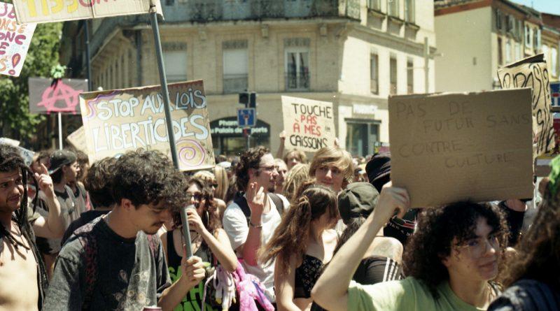 photo argentique de jeunes manifestants avec des pancartes dans la ville de Toulouse. Une pancarte dit "touche pas à mes caissons" .Une autre "Stop aux lois libertivides"